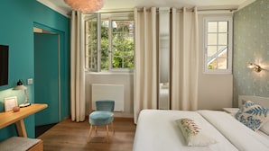 Un dormitorio con cama, escritorio, silla, ventana con cortinas y una lámpara fijada a la pared.