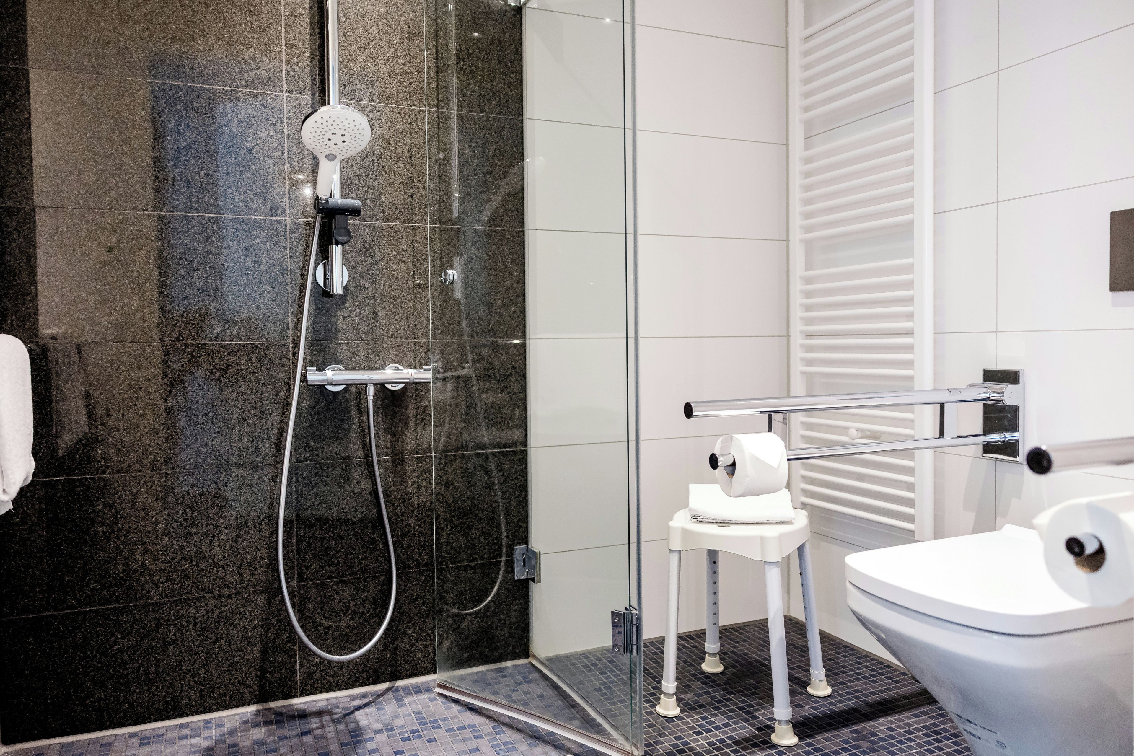 Un baño moderno con ducha de vidrio, inodoro y toallero.