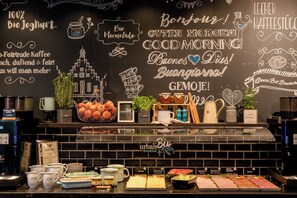 Una barra de desayuno con una pared de pizarra que muestra diferentes opciones para el desayuno y saludos en varios idiomas.