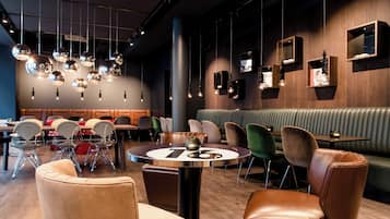 Un interior de restaurante moderno con mesas redondas, sillas de cuero y lámparas esféricas colgantes.