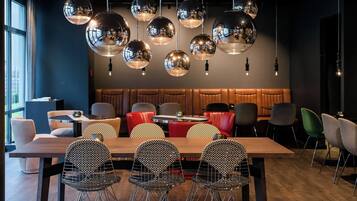A modern dining area with a wooden table and metal chairs, surrounded by red and grey upholstered booths.