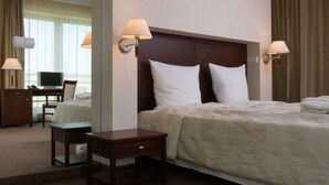 A hotel room with a large bed, two bedside lamps, a desk with a chair, and a television. - Hotel Kuracyjny (Gdynia)