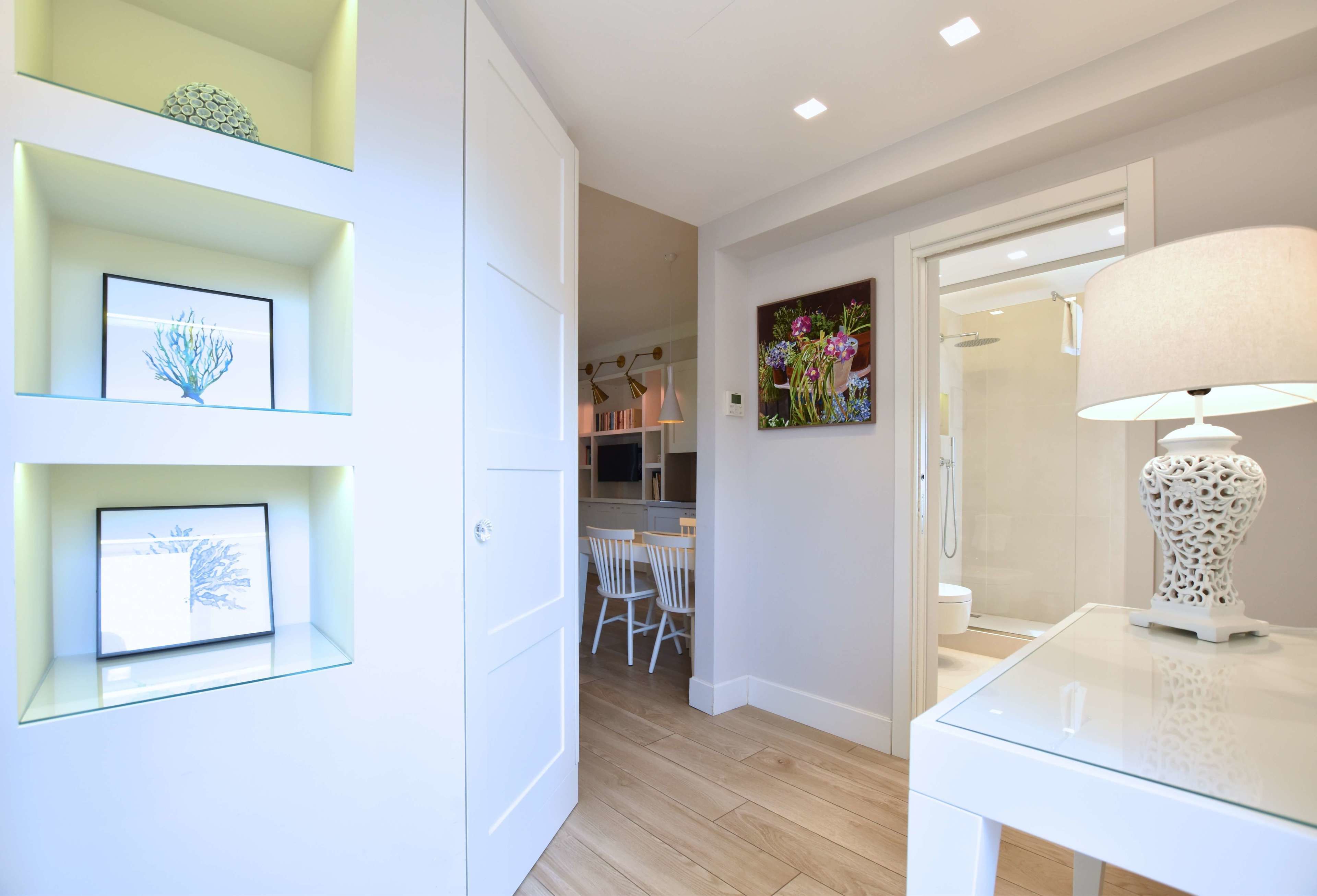 A modern interior with a glass table, white walls, and a dining area with chairs.