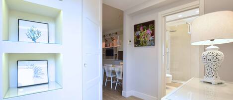 A modern interior with a glass table, white walls, and a dining area with chairs.