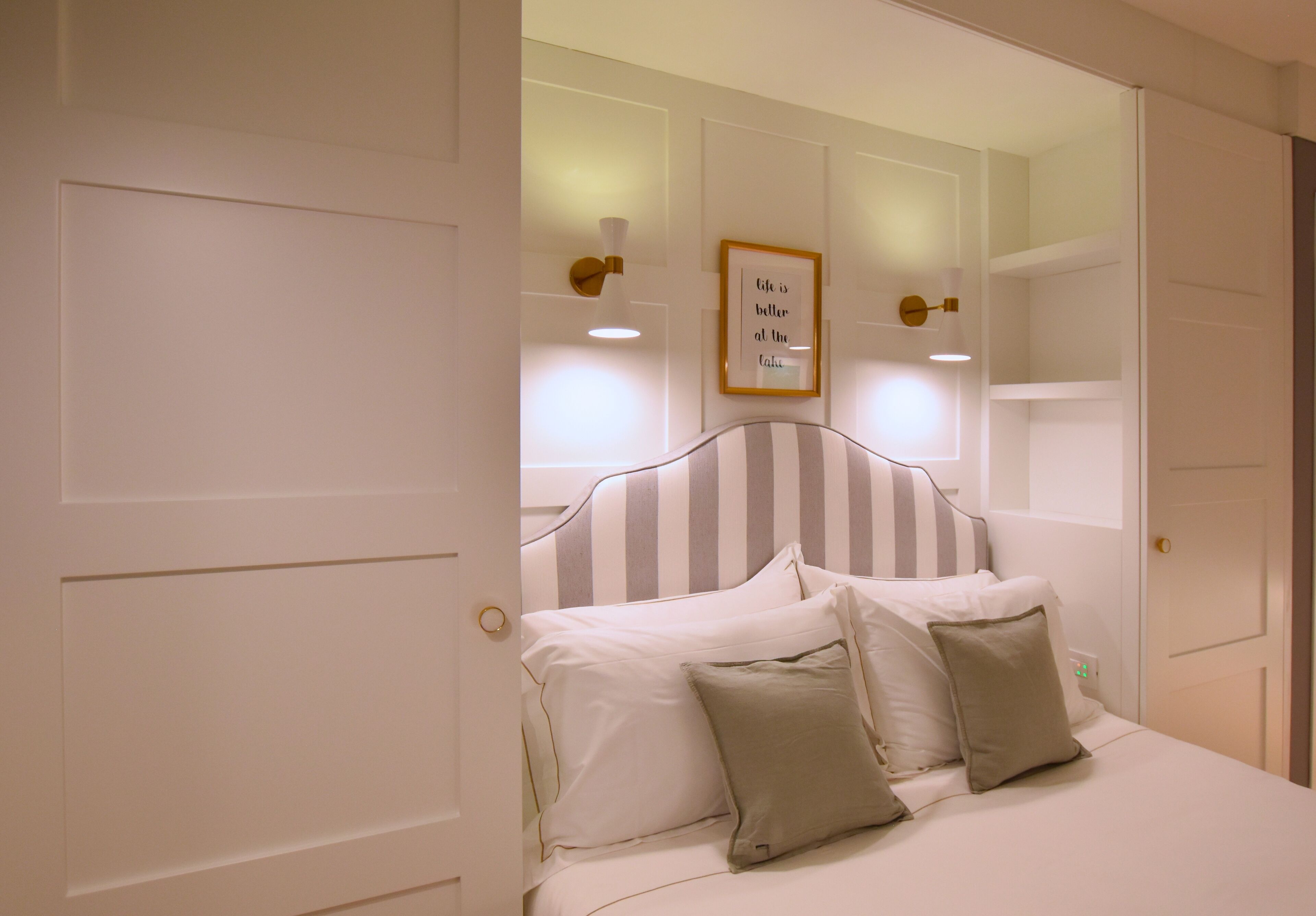 Una cama bien hecha con almohadas y una cita enmarcada en la pared.