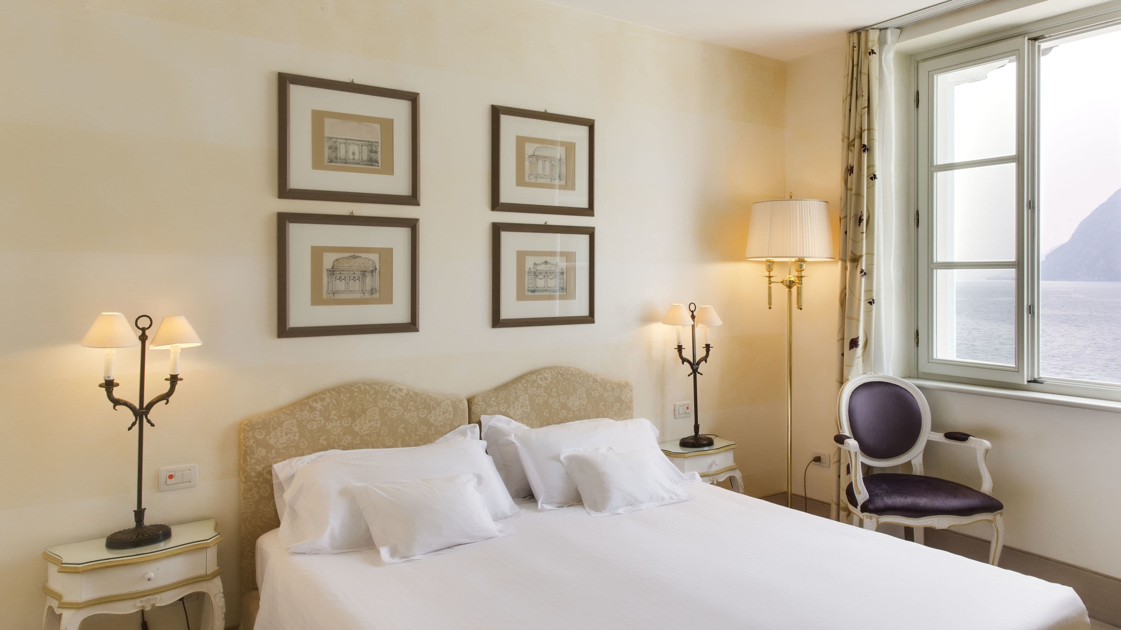 A hotel room with a bed, two bedside tables with lamps, a chair, and a window with a view.