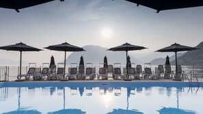 A poolside area with sun loungers and umbrellas, overlooking a body of water and mountains. - Hotel Rivalago (Sulzano)