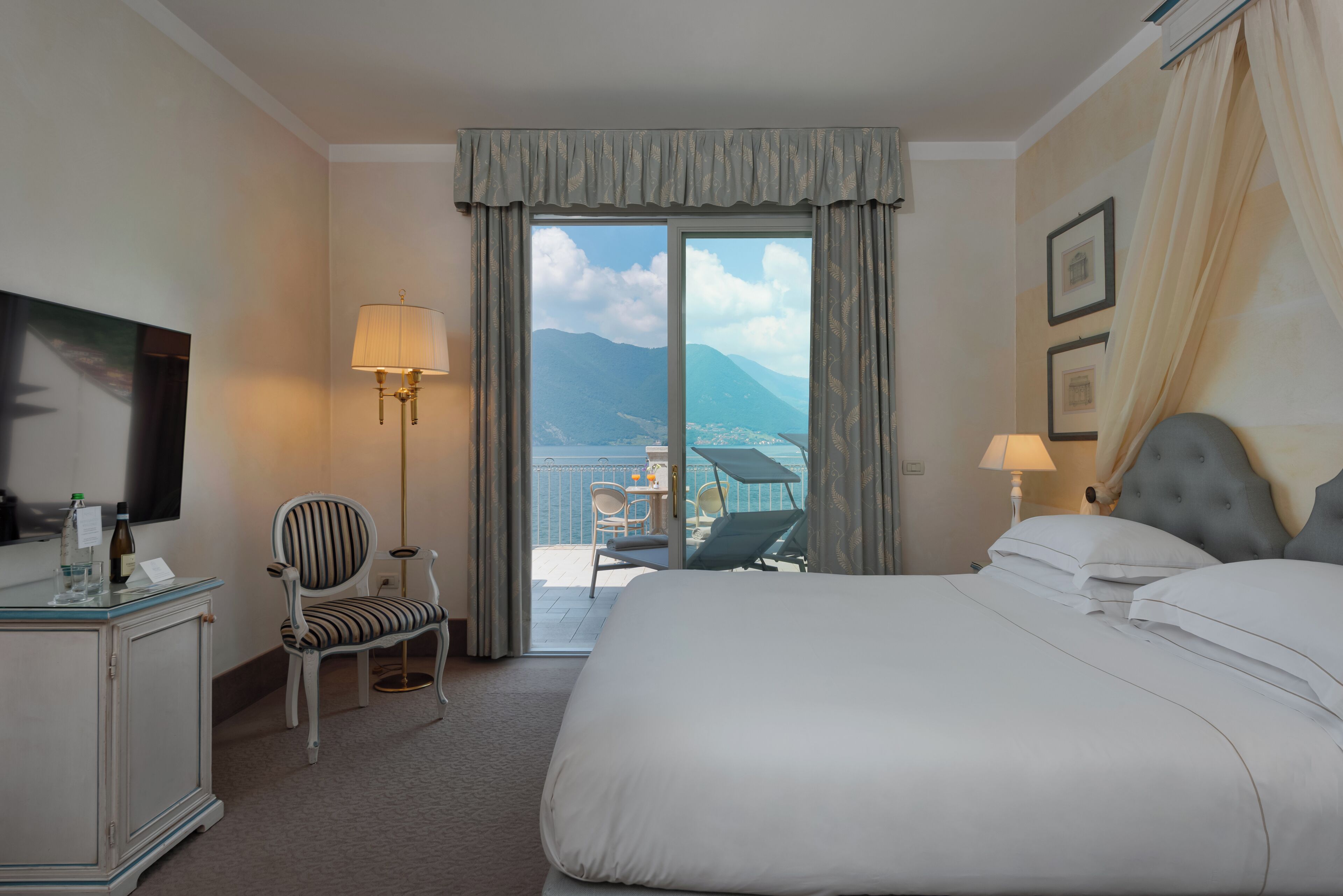 Habitación de hotel con cama, una silla, un escritorio, una lámpara y vista al mar.