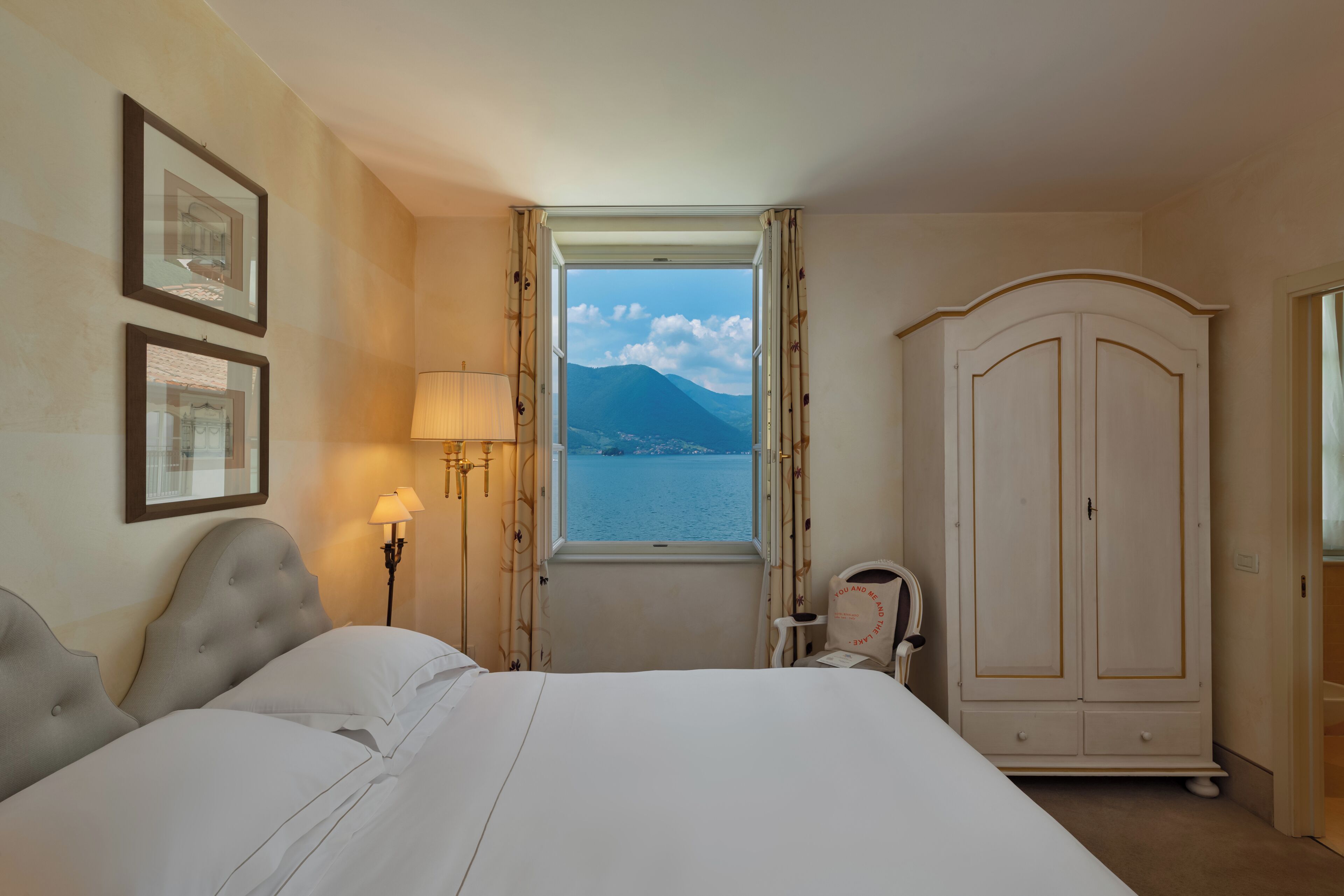 Habitación de hotel con cama, armario, ventana con vistas a la montaña y lámparas de pared.