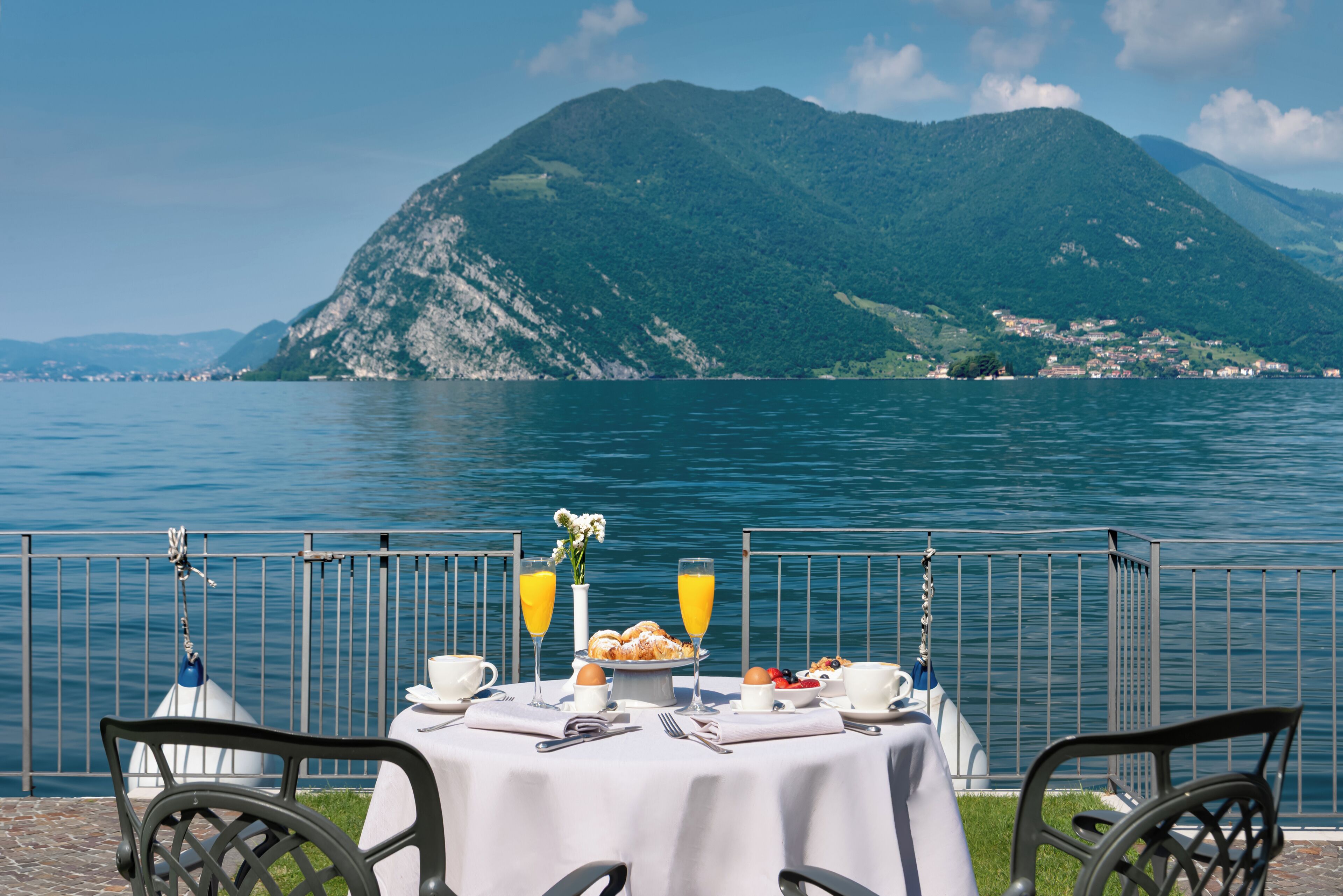Una mesa con alimentos para el desayuno y vistas a un lago y montañas.