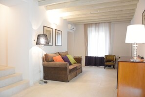 A living room with a sofa, a chair, a lamp, and a staircase. - Hotel Rivalago (Sulzano)