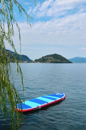 A calm lake with a paddleboard, a distant island, and a clear sky.