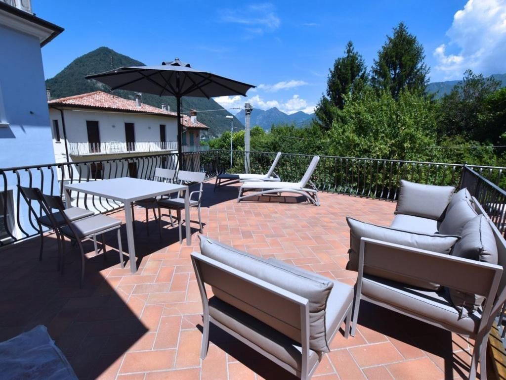 An outdoor patio with a table and chairs, a bench, and an umbrella.