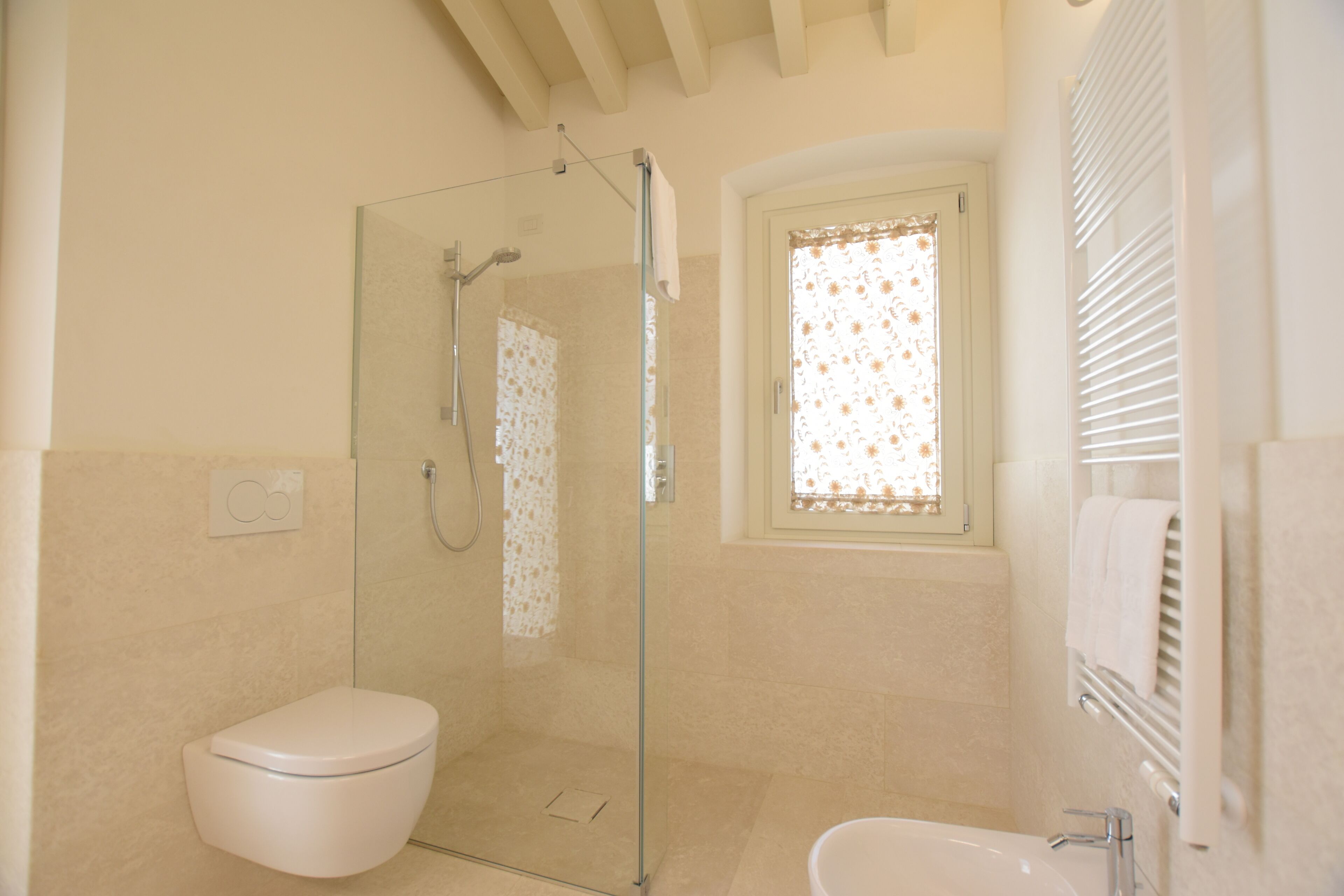 A bathroom with a glass-enclosed shower, a toilet, and a sink.