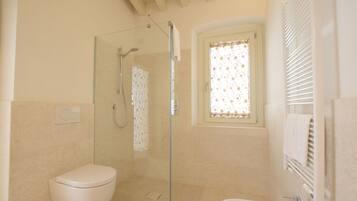 A bathroom with a glass-enclosed shower, a toilet, and a sink.