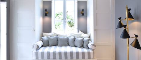 A room with a built-in window seat, two wall-mounted lamps, and a floor lamp.