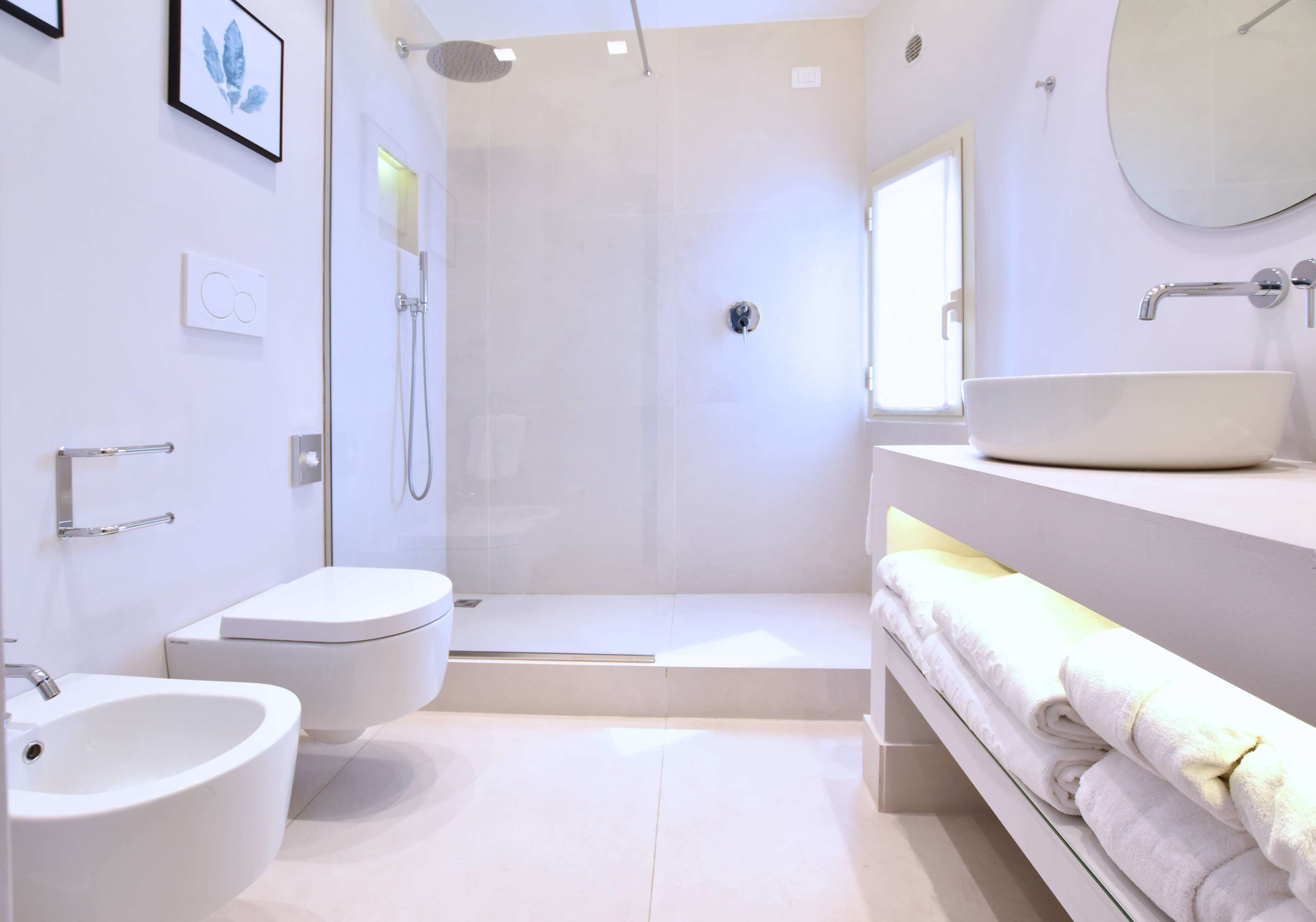 Un baño moderno con cabina de ducha, un bidé, un lavamanos y un mueble de tocador con toallas.