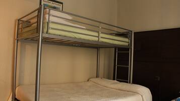 A bunk bed with a sign above it, a wooden wardrobe, and a wall-mounted shelf.