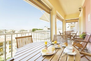 A balcony with a table set for breakfast, including plates with food and drinks, wooden chairs, and a view of the cityscape. - Hotel Carlos V (Granada)