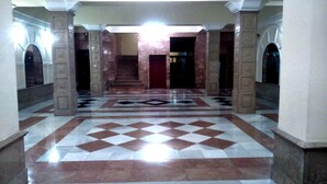 A spacious lobby with a checkered floor, marble columns, and a staircase leading to an upper level. - Hotel Carlos V (Granada)