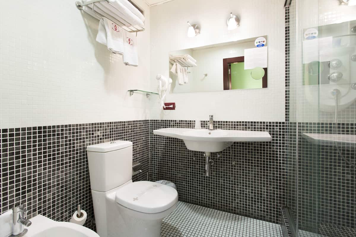 A bathroom with a toilet, sink, and shower.