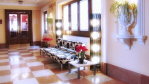 A checkered floor, a patterned sofa, a small table with a vase, and a wall-mounted plant. - Hotel Carlos V (Granada)