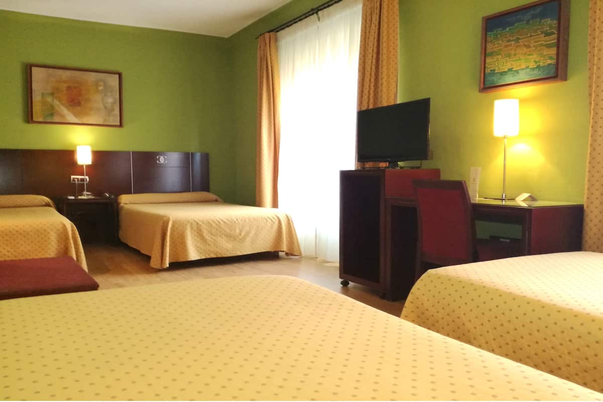 A hotel room with two beds, a desk, a TV, and a painting on the wall.