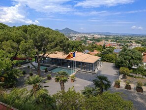 A modern building with a glass facade, a pool, and a flag. - Hotel El Castell (Sant Boi de Llobregat)