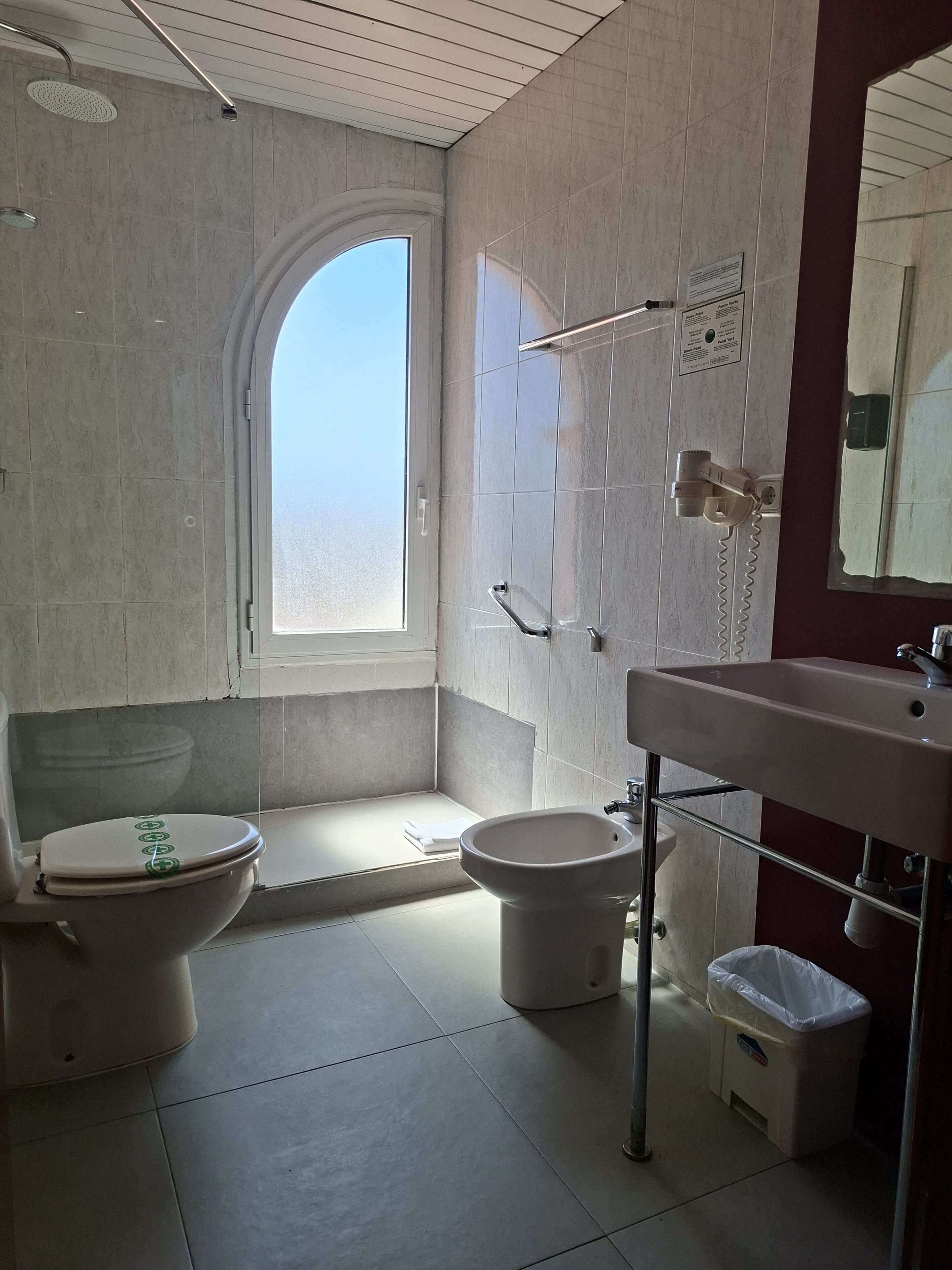 Une salle de bain comprenant des toilettes, un bidet, un lavabo et une douche.