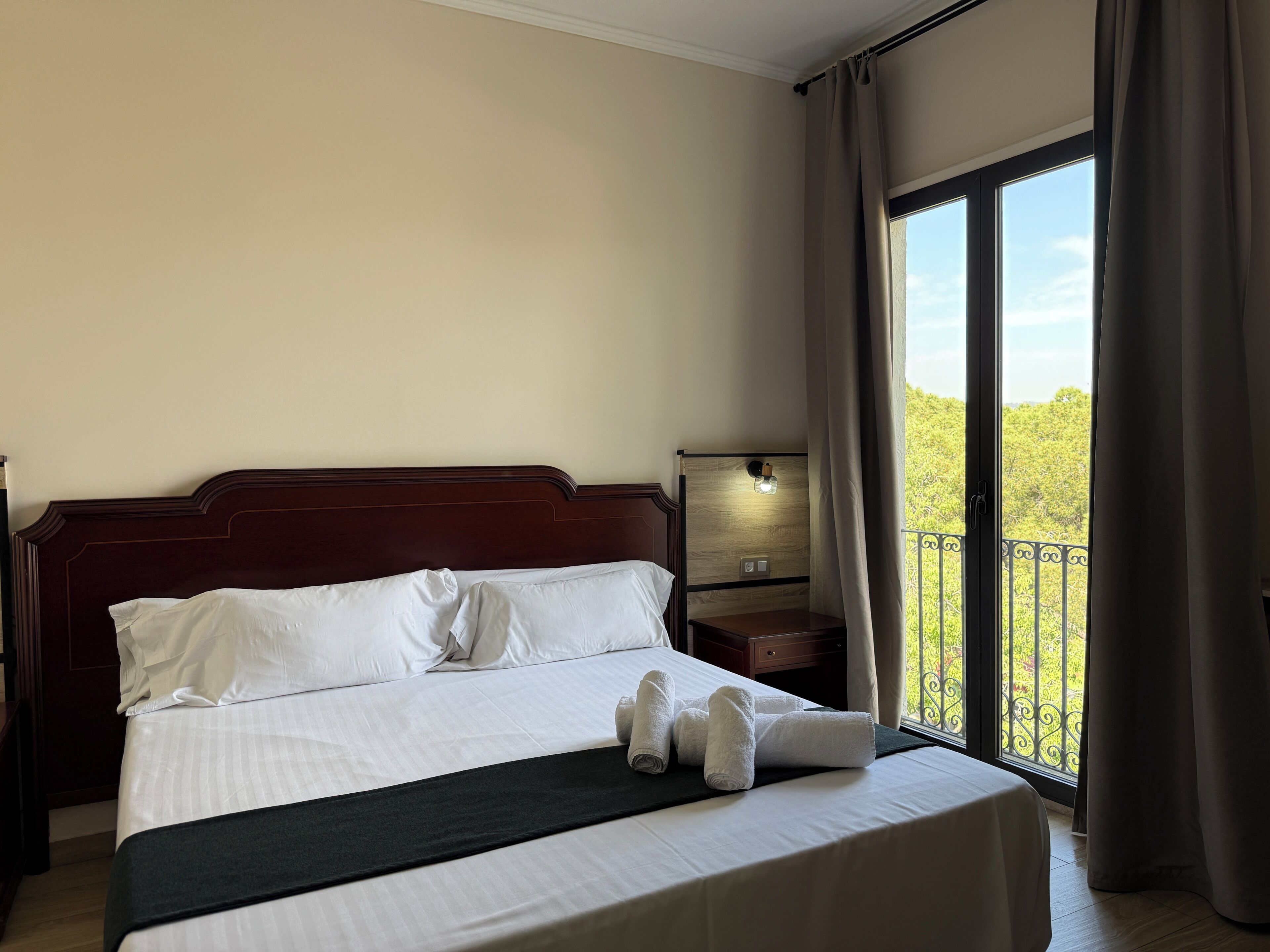 Une chambre d’hôtel avec un lit, une table de chevet, une lampe et un balcon avec vue.