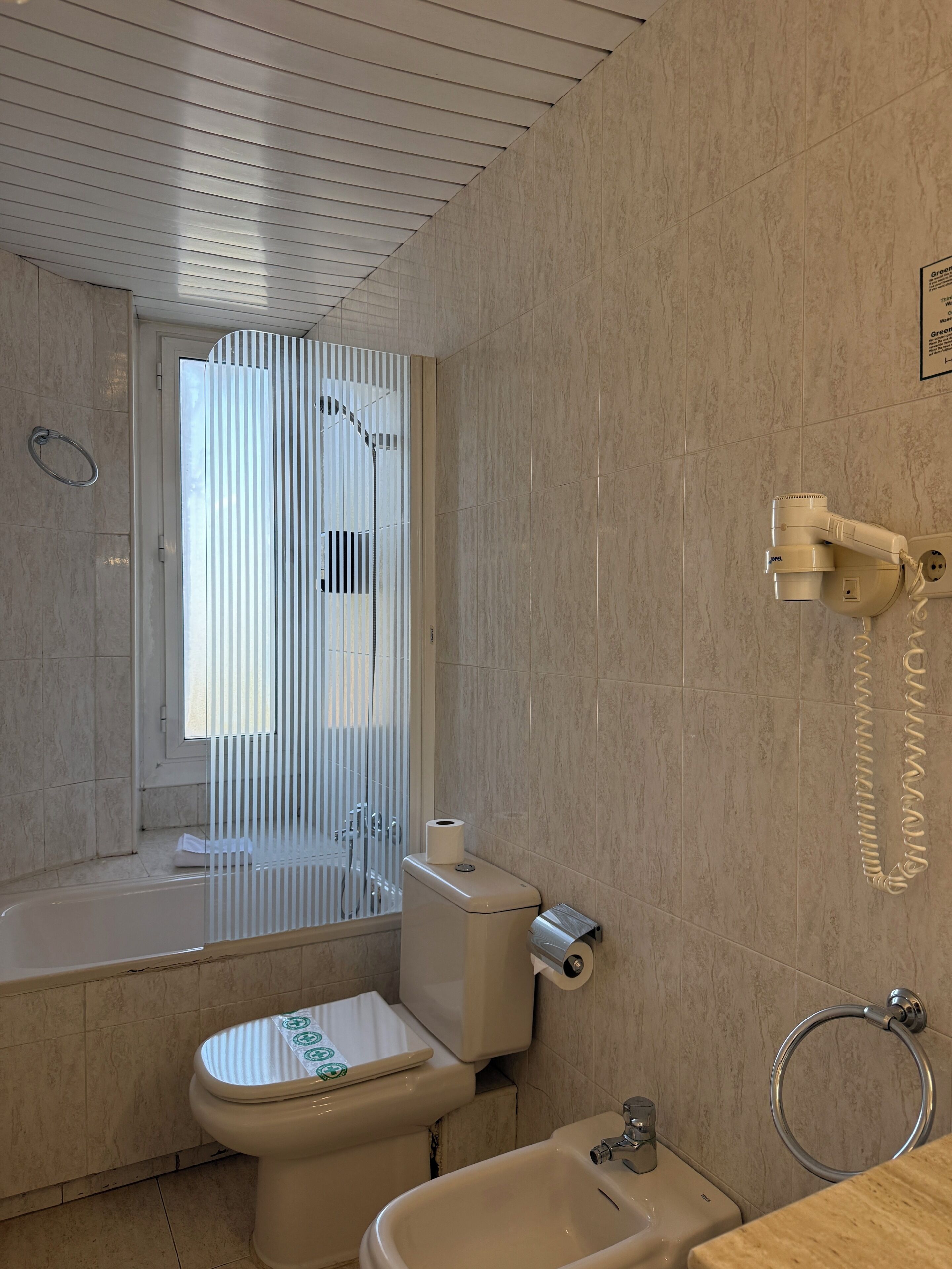 Un baño con inodoro, bidé, bañera y argolla para toallas.