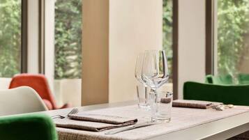 A dining table set with a placemat, a wine glass, and a water glass, with chairs around it.