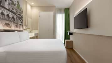 Een moderne hotelkamer met een groot bed, een flatscreen televisie aan de muur, een badkamer met een wastafel en spiegel, en een groen gordijn.