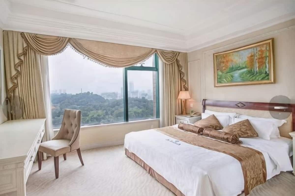 Ein Hotelzimmer mit einem großen Bett, einem Schreibtisch, einem Stuhl und einem Fenster mit Blick auf die Stadt.