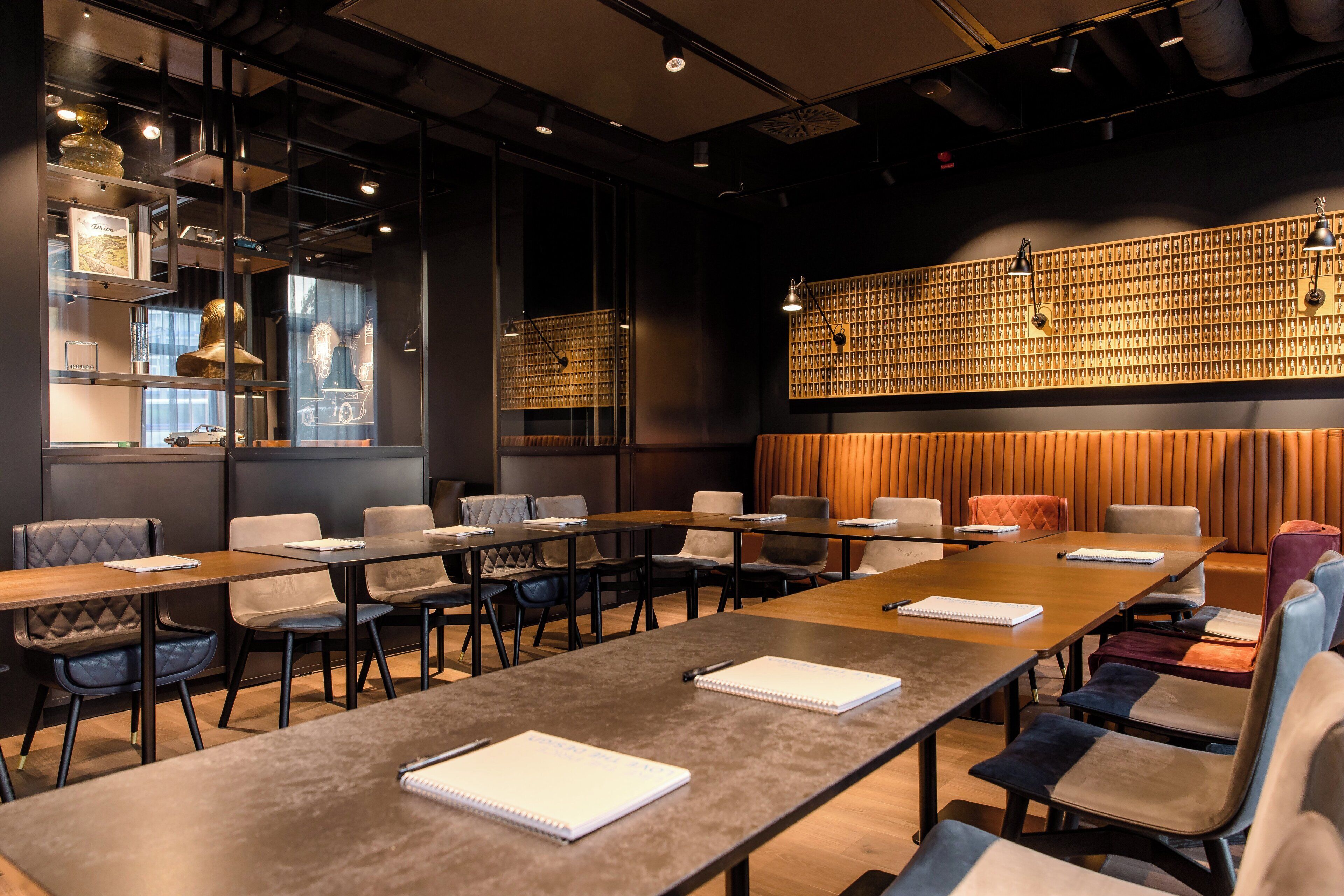 A modern conference room with long tables, comfortable seating, and a decorative wall with a geometric pattern.