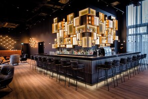 Un espace bar au design moderne, doté d’une structure centrale illuminée et de plusieurs types d’aménagements pour s’asseoir.