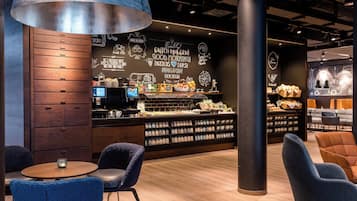 Una cafetería moderna con mostrador de madera, zona de estar y decoración en la pared.