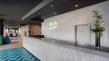 A modern reception area with a welcoming sign, a private room door, and a decorative plant.