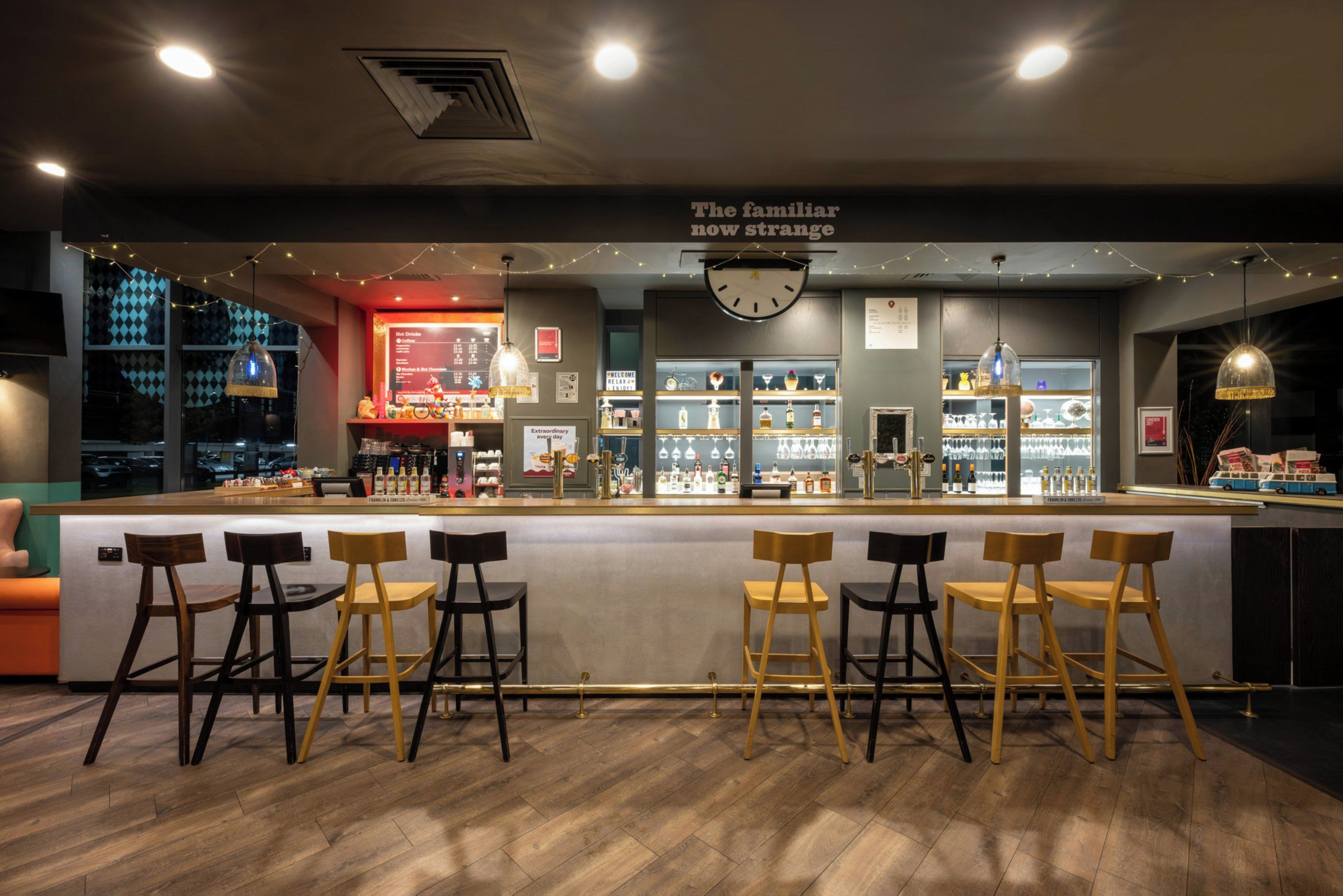A bar area with a counter, stools, and a clock above.