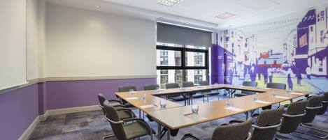 A conference room with a long table, chairs, and a large window.