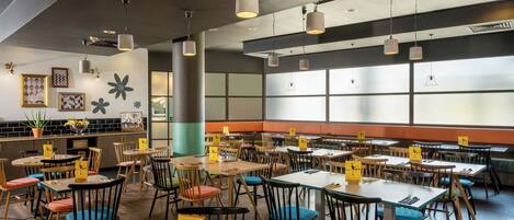 A restaurant with round tables and chairs, a bar area, and a large window with a view.
