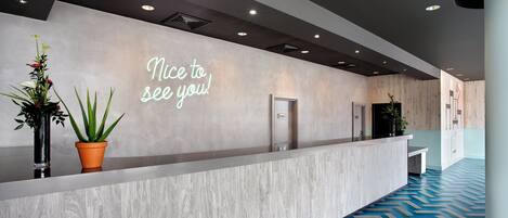 Un área de recepción moderna con un letrero de bienvenida, un mostrador de recepción y un piso con diseño.