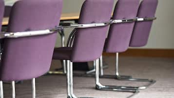 Una hilera de sillas moradas con patas cromadas y estructura metálica, dispuestas en un aula o salón de reuniones.