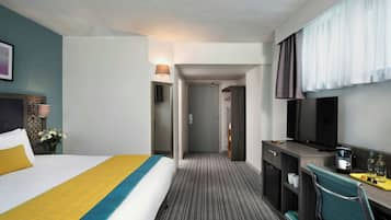 A hotel room with a bed, a desk, a television, and a bathroom.