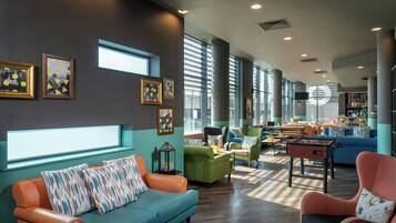 A modern lounge area with a sofa, armchairs, and a foosball table.