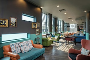 A modern lounge area with a sofa, armchairs, and a foosball table. - Leonardo Hotel Brighton (Brighton)