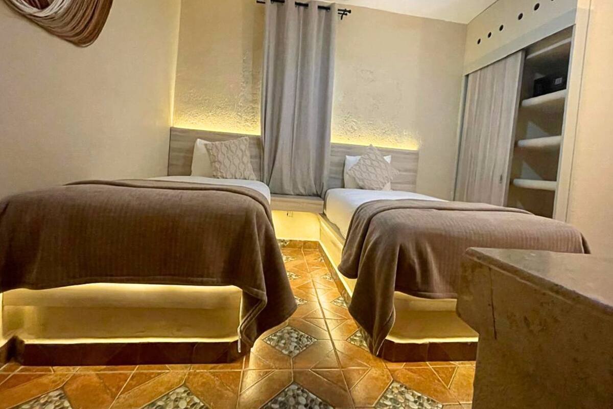 A hotel room with two beds, a small seating area, and a wardrobe.