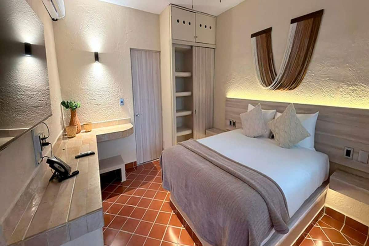 A bedroom with a bed, bedside table, lamp, and a wardrobe.