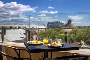 A table with breakfast items including eggs, toast, and orange juice, overlooking a cityscape with traditional architecture. - Ayvazovsky (Odesa)