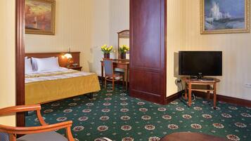 A hotel room with a bed, a desk with a chair, a television, and a sofa.
